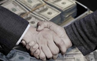 two men shaking hands over backdrop of cash