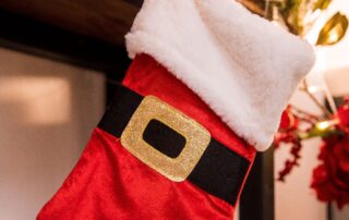 Red Christmas themed stocking hanging over a fireplace